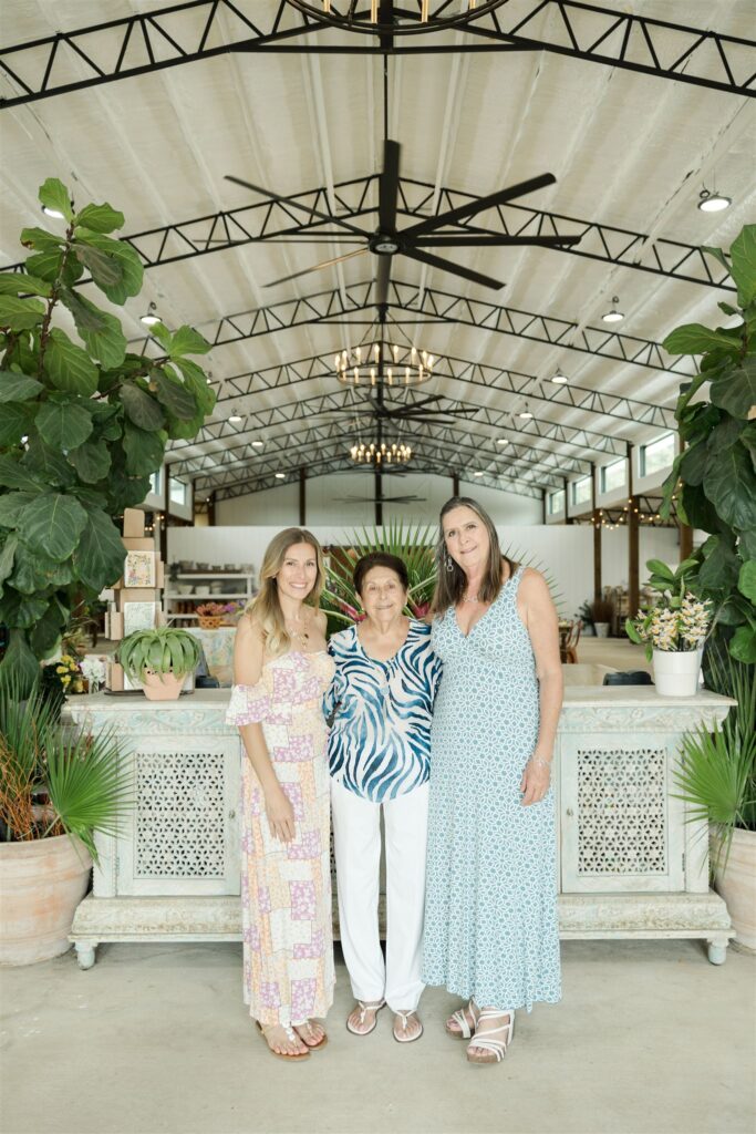 Daughter, mother, and grandmother smiling together at Blooming Freedom nursery and event venue in Palm City