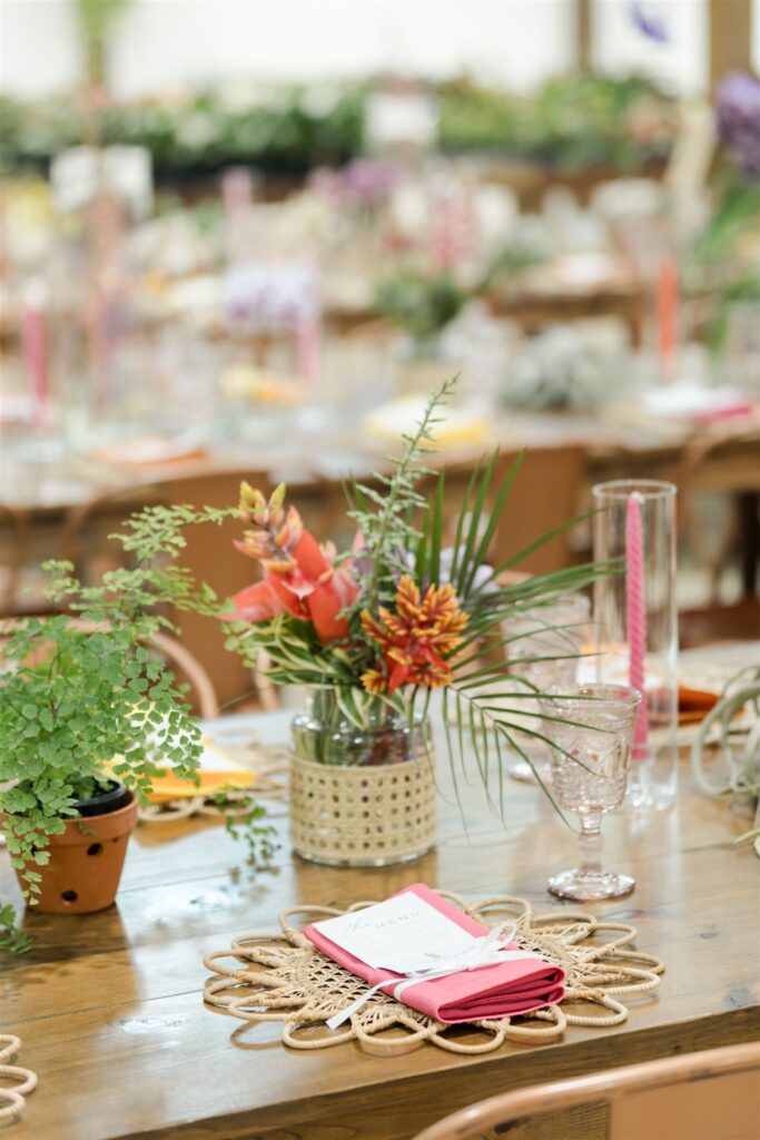Colorful wedding table decor with woven chargers, tropical florals, and bright napkins at Blooming Freedom event in Palm City
