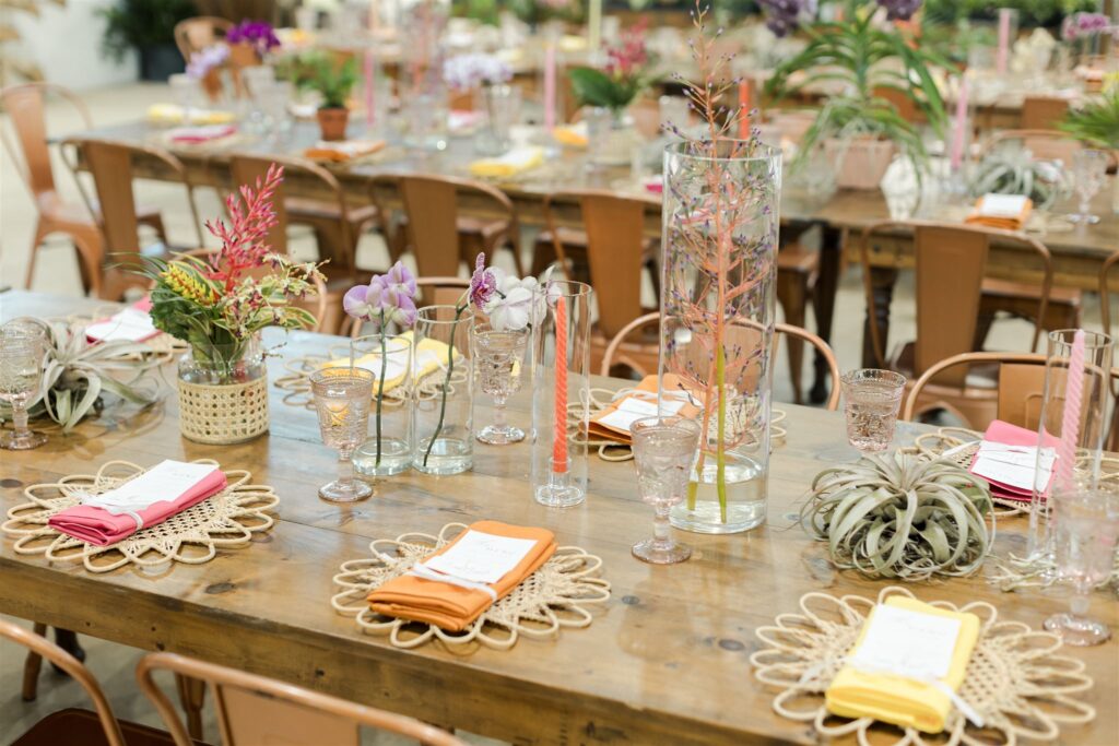 Colorful wedding table decor with woven chargers, tropical florals, and bright napkins at Blooming Freedom event in Palm City