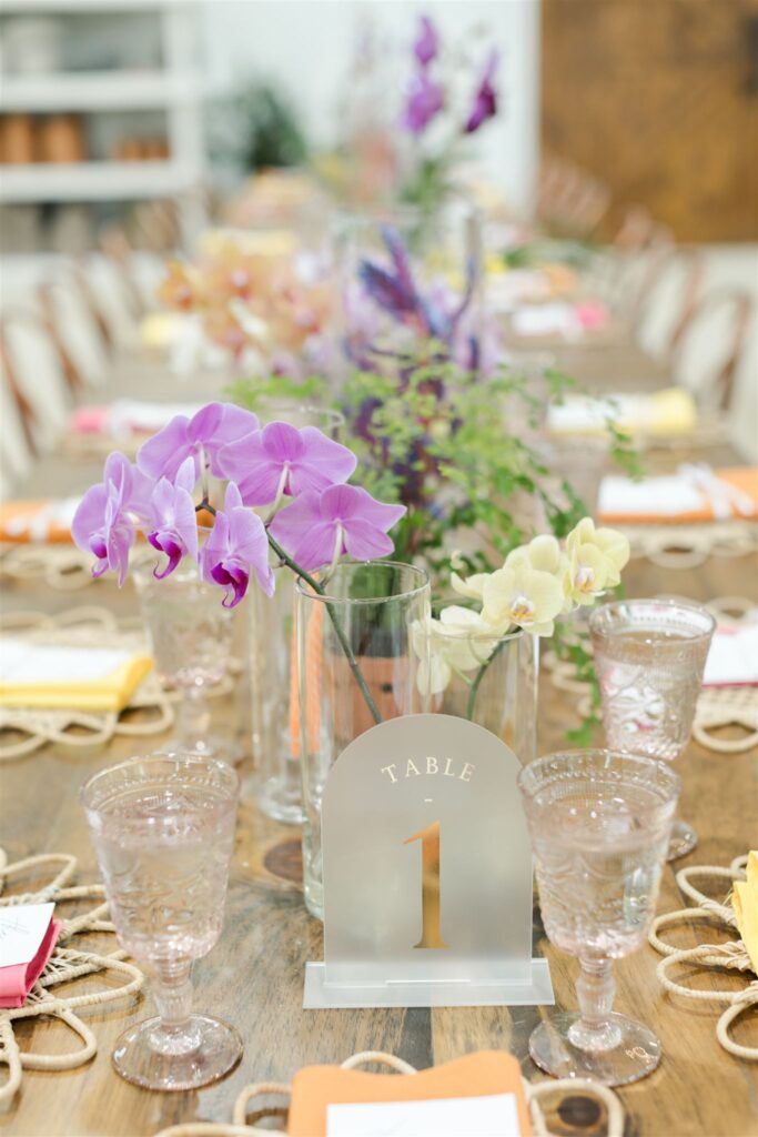 Colorful wedding table decor with woven chargers, tropical florals, and bright napkins at Blooming Freedom event in Palm City
