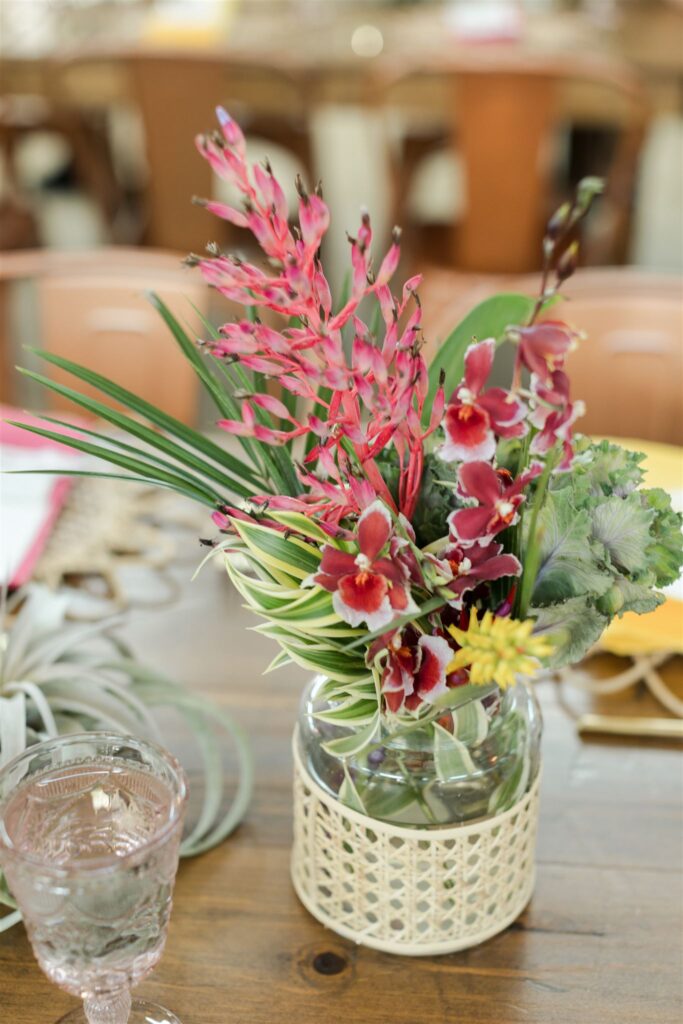 Close-up of vibrant tropical floral arrangement with orchids and lush greenery by Sarandipity Florals at Blooming Freedom venue