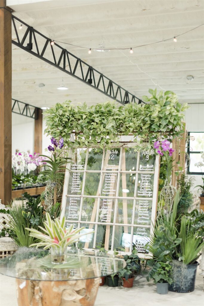 Vintage windowpane seating chart with greenery and orchids displayed indoors at Blooming Freedom event venue in Palm City
