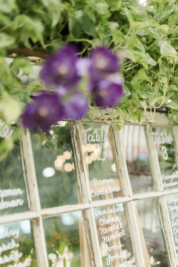 Vintage windowpane seating chart with greenery and orchids displayed indoors at Blooming Freedom event venue in Palm City