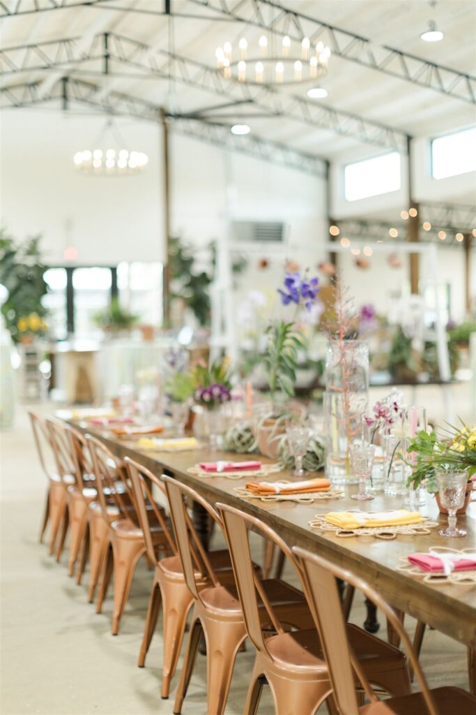 Colorful wedding table decor with woven chargers, tropical florals, and bright napkins at Blooming Freedom event in Palm City
