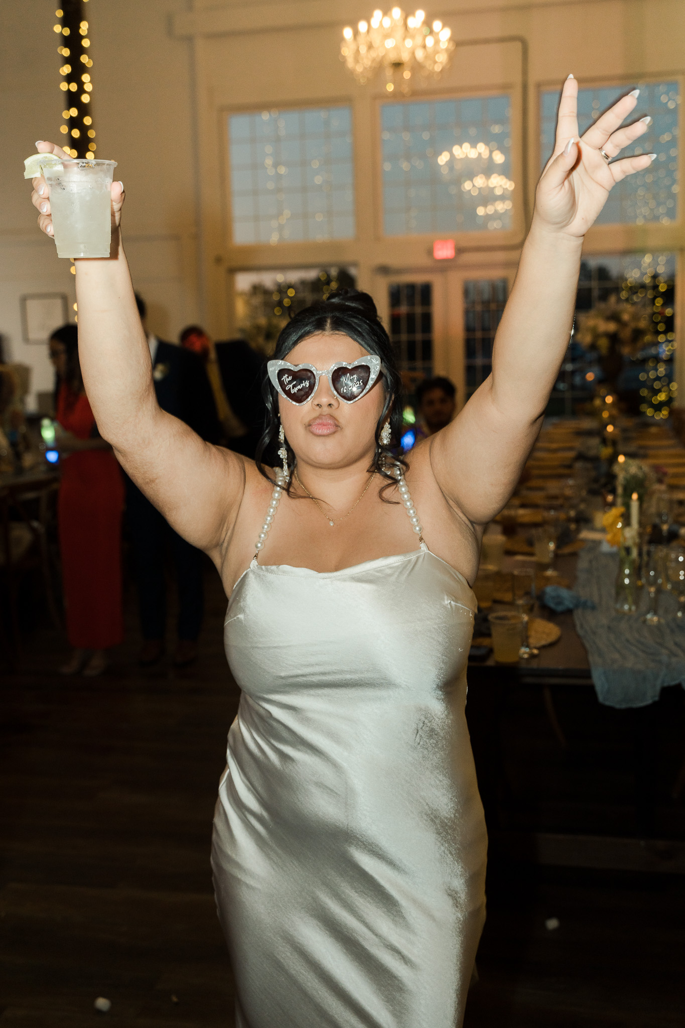 Bride celebrating on the dance floor in heart-shaped wedding glasses, photographed by Nassimbeni Photo & Films.
